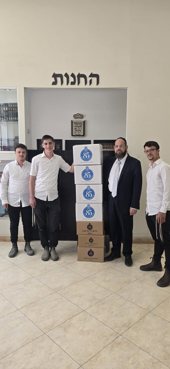 הזוכה המאושר עם ארגזי הספרים. לצידו, יו"ר מוסד הרב קוק, הרב יהודה רפאל