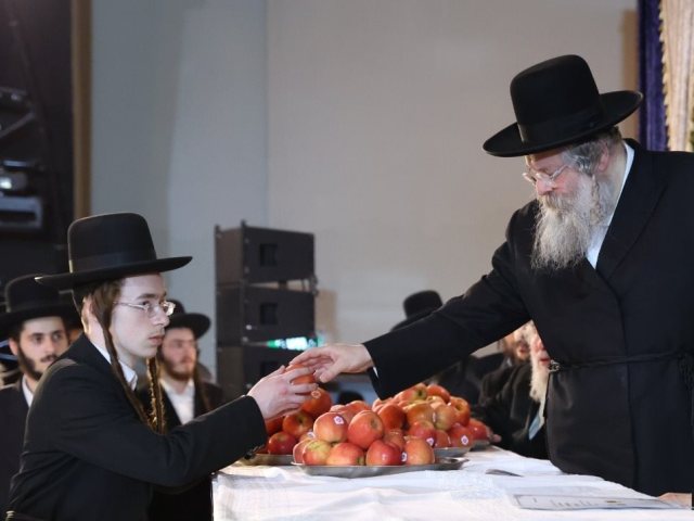 הרב נחמיה אלתר מחלק תפוחים לבחורים המצטיינים. תמונה לפי תקנה 27 לחוק ז"י